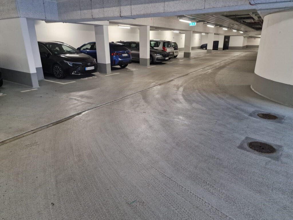 Belegte Tiefgaragen-Parkplätze von Ferien-Parken Stuttgart in der Magellanstraße (Leinfelden Echterdingen) in der Nähe des Flughafen Stuttgart. Vier Autos stehen nebeneinander in den Parklücken, während weiter hinten noch alle Parkplätze frei sind.